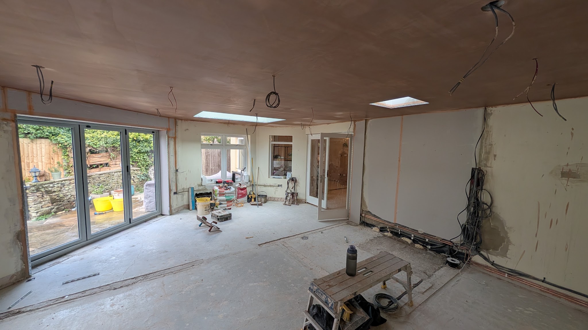 Large open-plan extension with bifold doors, boarded out and ready for plaster