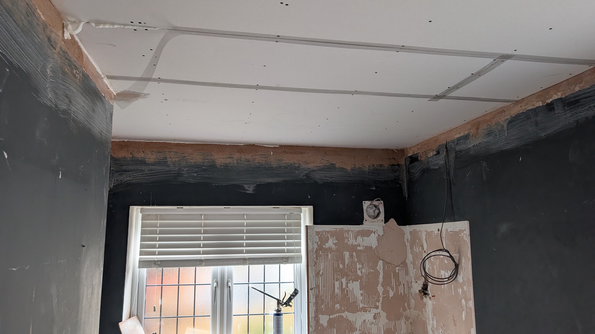 Room part way through a job, with the ceiling boarded and the walls being prepared