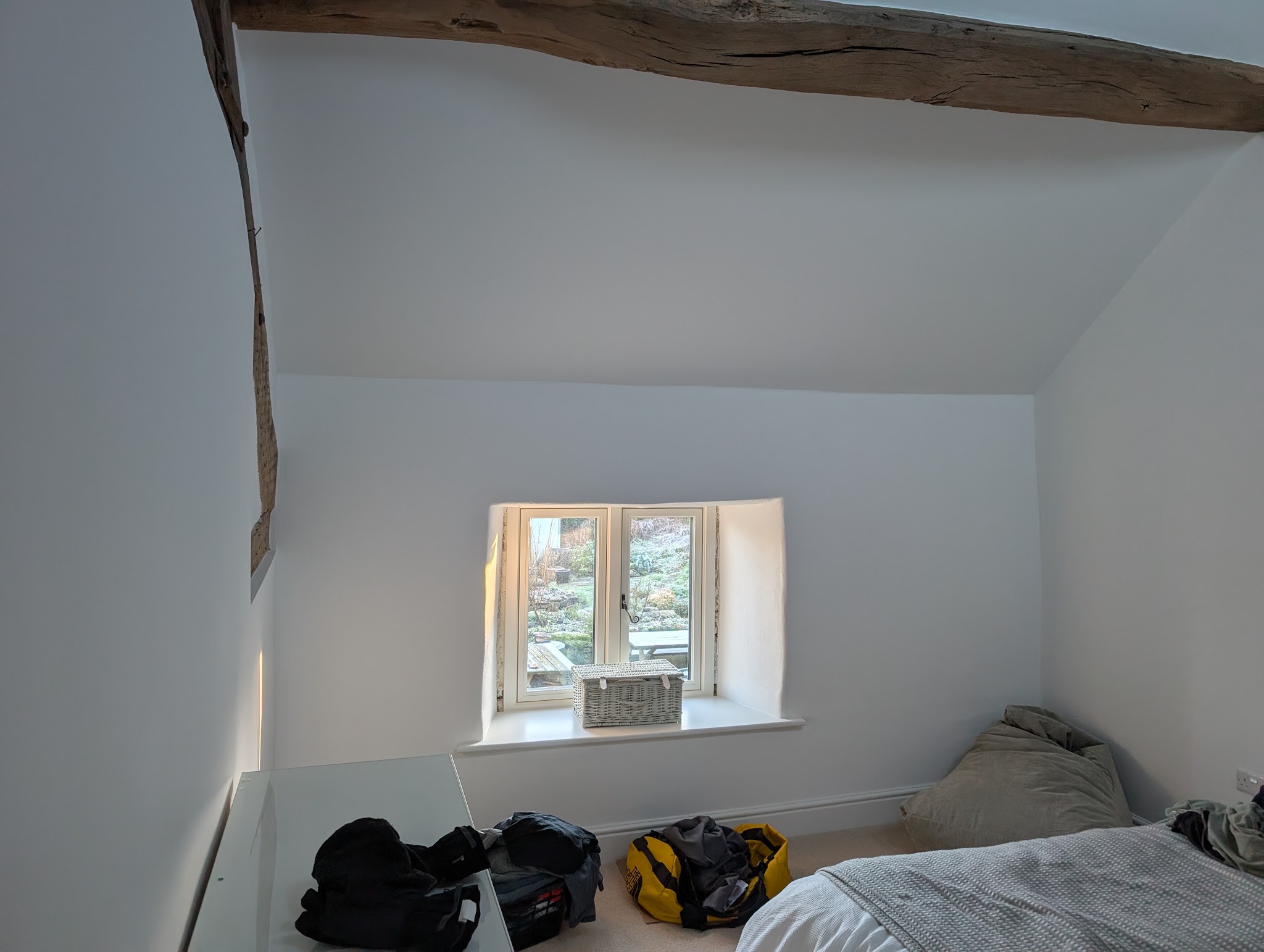 Finished loft bedroom with smooth white walls and an exposed timber beam